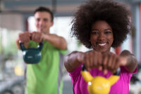 Man and woman lifting kettle bell weights.